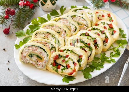 Hors-d'œuvre créatifs noël. Rouleaux de fromage avec bâtonnets de crabe, fromage à la crème, œufs et fromage à la crème, poivron doux, légumes verts. Banque D'Images