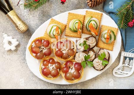 Hors-d'œuvre créatifs pour noël. Sapins de Noël de jambon, concombre, fromage et étoile de carotte sur des craquelins, tartelettes à la chicke Banque D'Images