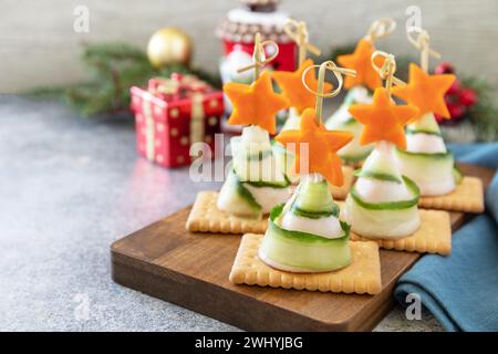 Hors-d'œuvre créatifs noël. Sapins de Noël de jambon, concombre, fromage et étoile de carotte sur des craquelins sur la table de fête. COP Banque D'Images