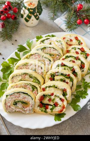 Hors-d'œuvre créatifs noël. Rouleaux de fromage avec bâtonnets de crabe, fromage à la crème, œufs et fromage à la crème, poivron doux, légumes verts. Banque D'Images