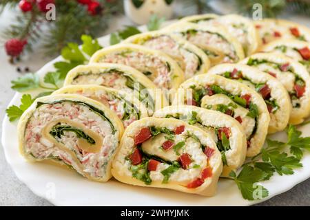 Hors-d'œuvre créatifs noël. Rouleaux de fromage avec bâtonnets de crabe, fromage à la crème, œufs et fromage à la crème, poivron doux, légumes verts. Banque D'Images