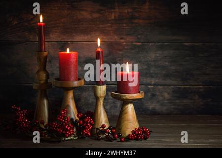 Quatre bougies rouges dans des bâtons de bougie en bois dans une rangée comme décoration de l'Avent ou de Noël sur un fond rustique foncé, HO naturel Banque D'Images