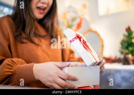 Heureuse femme asiatique ouvre boîte de Noël et surprises. préparation de surprise pour noël présent en vacances Banque D'Images