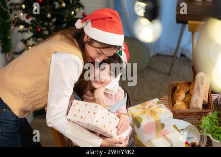 La petite fille reçoit des cadeaux des membres de sa famille pendant le dîner de Noël à la maison. Banque D'Images