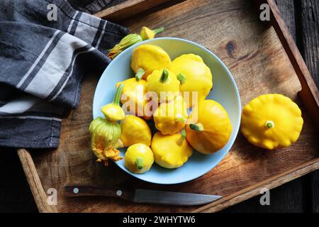 Patisson jaune, légume de courge Saint-Jacques de pattypan sur plaque bleue sur fond de table en marbre blanc. Vue de dessus, pose à plat. Automne, f Banque D'Images