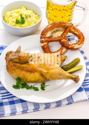 Poulet à moitié rôti, bière, bretzel et salade de pommes de terre Banque D'Images