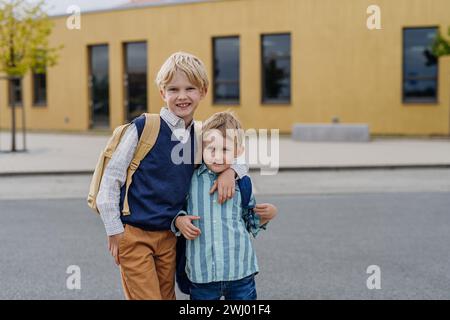 Portrait de deux frères devant le bâtiment de l'école. La notion de conciliation travail-vie familiale pour les parents. Banque D'Images