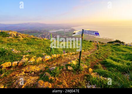 Arbel, Israël - 09 février 2024 : vue au lever du soleil sur la mer de Galilée et la réserve naturelle du mont Arbel, avec un sentier pédestre et un panneau de direction, Nord Banque D'Images