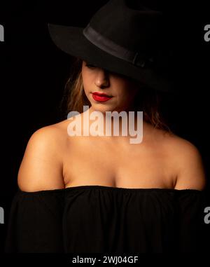 Portrait à contraste élevé d'une femme caucasienne séduisante portant un chapeau noir Banque D'Images