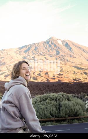 Un jeune homme joyeux est photographié profitant de la toile de fond à couper le souffle de la montagne Teide baignée dans la lueur chaude d'un coucher de soleil. Banque D'Images