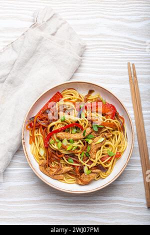 Bol blanc avec Chow Mein ou Lo Mein, nouilles sautées chinoises traditionnelles avec viande et légumes, servies avec baguettes Banque D'Images