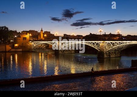 Pont Triana - Puente de Isabel II sur la rivière Guadalquivir au crépuscule dans la ville de Séville, Andalousie, Espagne. Banque D'Images