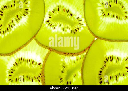 Tranches de kiwi illuminées. Coupes transversales de kiwi projetés en arrière isolées sur blanc. Résumé Banque D'Images