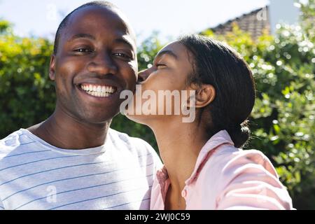 Jeune homme afro-américain reçoit un baiser sur la joue d'une femme biraciale Banque D'Images