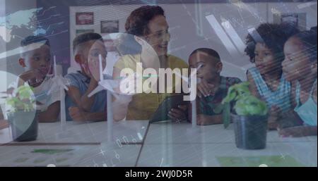 Image du traitement des données sur des enseignantes et des élèves heureux et diversifiés avec des éoliennes Banque D'Images