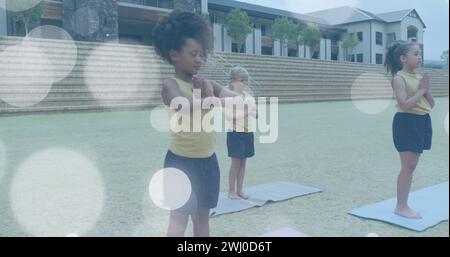 Image de taches de lumière blanche au-dessus de heureux diverse faisant du yoga en classe en plein air Banque D'Images