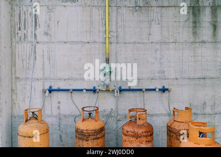 Bouteilles de gaz raccordées à des tuyaux sur un mur en béton Banque D'Images