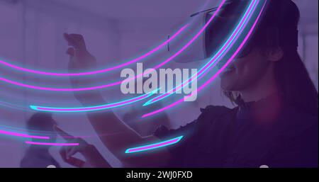 Image de traînées lumineuses incandescentes de transfert de données sur une femme biraciale à l'aide d'un casque vr Banque D'Images