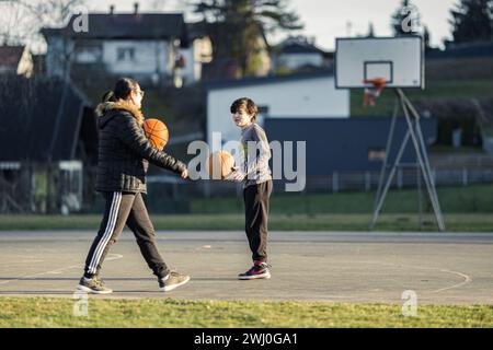 Une grand-mère et son petit-fils jouant au baksetbbal en plein air sur un court en automne Banque D'Images