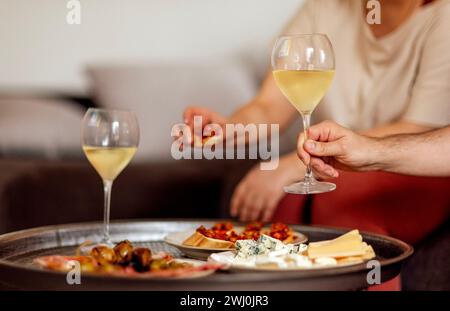 Deux verres de champagne frais et des assiettes avec divers en-cas sur une table basse ronde en métal Banque D'Images