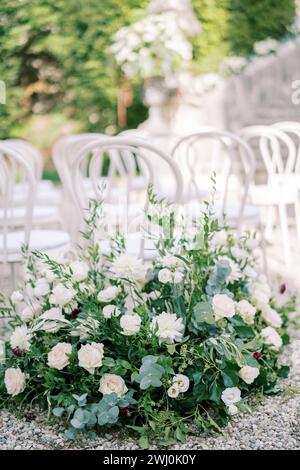 Un grand bouquet de fleurs se dresse près des chaises blanches dans le parc Banque D'Images
