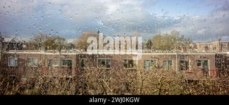 Vitre pleine de gouttes de pluie donnant sur le quartier résidentiel à Utrecht, aux pays-Bas. Ambiance cinématographique hollandaise Banque D'Images