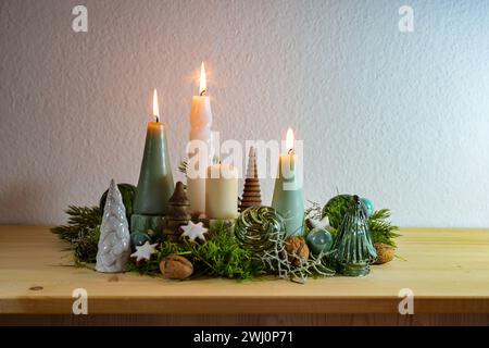 Troisième Avent, décoration avec quatre bougies différentes, trois sont allumées, un peu de mousse, boules de Noël vertes de verre et cannelle St Banque D'Images