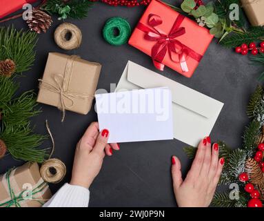 Enveloppe blanche et couronne de Noël sur fond noir, vue de dessus Banque D'Images