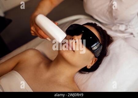 Jeune femme qui reçoit une épilation photo lors d'une visite au centre de beauté dans un salon de beauté Banque D'Images