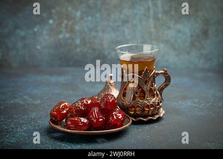 Pause jeûne avec dattes séchées pendant le Ramadan Kareem, repas iftar avec dattes et thé arabe dans un verre traditionnel, vue d'angle sur Banque D'Images