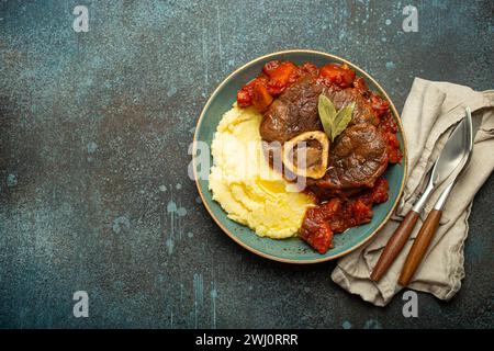 Plat traditionnel italien Ossobuco tout milanais fait avec de la viande de jarret de veau coupée avec une sauce tomate végétale servie avec du polent de maïs Banque D'Images