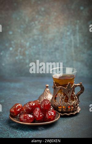 Pause jeûne avec dattes séchées pendant le Ramadan Kareem, repas iftar avec dattes et thé arabe dans un verre traditionnel, vue d'angle sur Banque D'Images