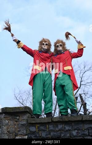 Herbstein, Allemagne. 12 février 2024. Deux singes, qui sont des figures traditionnelles, se dressent sur le mur de la ville pendant le Herbstein Springerzug. Les tailleurs de pierre tyroliens ont apporté la tradition à Herbstein au XVIIe siècle. Plus de 50 chars ont pris part au traditionnel défilé Rose Monday dans la ville, située dans le quartier de Vogelsberg. Crédit : Uwe Zucchi/dpa/Alamy Live News Banque D'Images
