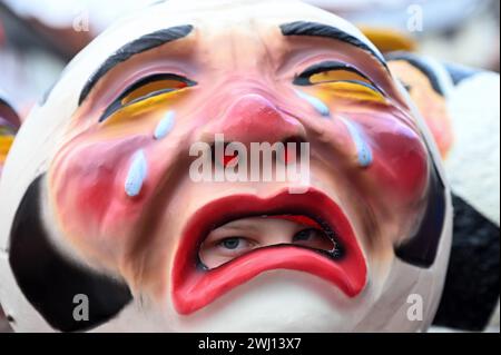 Herbstein, Allemagne. 12 février 2024. Les yeux d'un garçon peuvent être vus à travers la bouche d'un Schwellkopp dans le Herbstein Springerzug. Les tailleurs de pierre tyroliens ont apporté la tradition à Herbstein au XVIIe siècle. Plus de 50 chars ont pris part au traditionnel défilé Rose Monday dans la ville du district de Vogelsberg. Crédit : Uwe Zucchi/dpa/Alamy Live News Banque D'Images