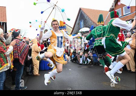 Herbstein, Allemagne. 12 février 2024. Les paires de chevaliers sont en action dans leurs costumes colorés pendant la procession des chevaliers Herbstein. Les tailleurs de pierre tyroliens ont apporté la tradition à Herbstein au XVIIe siècle. Plus de 50 chars ont pris part au traditionnel défilé Rose Monday dans la ville du district de Vogelsberg. Crédit : Uwe Zucchi/dpa/Alamy Live News Banque D'Images