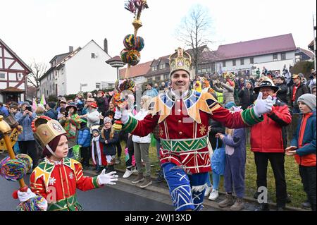 Herbstein, Allemagne. 12 février 2024. Bajazz Markus I (R), est en action dans son costume coloré à côté du petit Bajazz Ben (7), dont il est le parrain au Herbstein Springerzug. Les tailleurs de pierre tyroliens ont apporté la tradition à Herbstein au XVIIe siècle. Plus de 50 personnes ont participé au traditionnel défilé du lundi Rose dans la ville du district de Vogelsberg. Crédit : Uwe Zucchi/dpa/Alamy Live News Banque D'Images