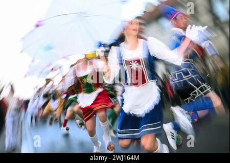 Herbstein, Allemagne. 12 février 2024. Les paires de chevaliers sont en action dans leurs costumes colorés pendant la procession des chevaliers Herbstein. Les tailleurs de pierre tyroliens ont apporté la tradition à Herbstein au XVIIe siècle. Plus de 50 chars ont pris part au traditionnel défilé Rose Monday dans la ville du district de Vogelsberg. (Photo avec effet rotatif) crédit : Uwe Zucchi/dpa/Alamy Live News Banque D'Images