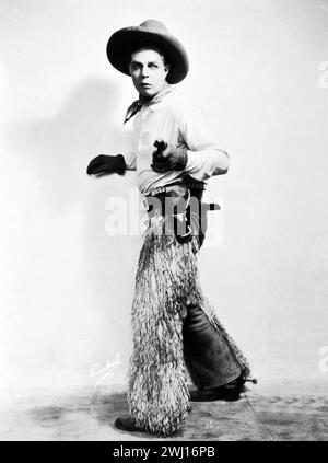 La star occidentale Hoot Gibson dans le rôle de Duke Travis dans Shootin' for Love (Universal, 1923). Portrait photo - tenue de cow-boy, tenant le revolver Banque D'Images