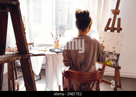 Jeune femme créative jolie artiste afro-américaine peint l'image avec des peintures à l'huile dans le studio d'art. Banque D'Images