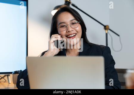 Femme d'affaires joyeuse parlant au téléphone dans le bureau Banque D'Images