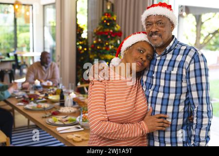 Heureux couple senior biracial embrassant et souriant au repas de noël avec des amis Banque D'Images