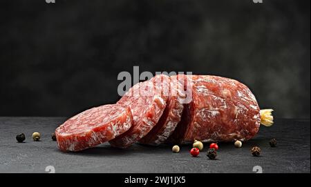 Saucisse traditionnelle italienne au salami sur fond noir Banque D'Images