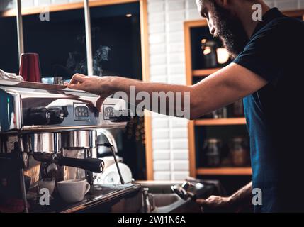 Gros plan des mains de barista préparant un cappuccino dans un gobelet en plastique pour le client au café. Banque D'Images