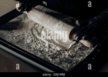 'Gros plan d'un rouleau à pâtisserie en action, façonnant habilement la pâte, capturant l'essence de l'artisanat de cuisson Banque D'Images