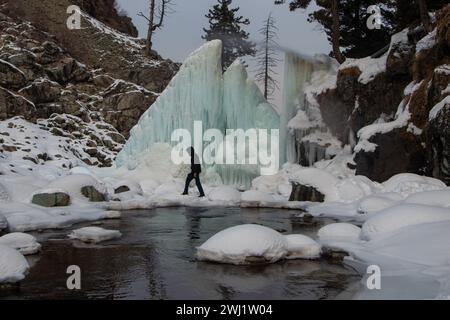 Baramulla, Jammu-et-Cachemire, Inde. 12 février 2024. Un homme est vu explorer la chute de glace gelée par une froide journée d'hiver à Tangmarg, Baramulla. Drung, un petit village situé à environ 50 km de la capitale, Srinagar, devient une destination touristique populaire cet hiver en raison des températures inférieures au point de congélation dans la vallée. (Crédit image : © Adil Abbas/ZUMA Press Wire) USAGE ÉDITORIAL SEULEMENT! Non destiné à UN USAGE commercial ! Banque D'Images