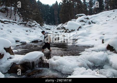 Baramulla, Jammu-et-Cachemire, Inde. 12 février 2024. Un homme est vu explorer la chute de glace gelée par une froide journée d'hiver à Tangmarg, Baramulla. Drung, un petit village situé à environ 50 km de la capitale, Srinagar, devient une destination touristique populaire cet hiver en raison des températures inférieures au point de congélation dans la vallée. (Crédit image : © Adil Abbas/ZUMA Press Wire) USAGE ÉDITORIAL SEULEMENT! Non destiné à UN USAGE commercial ! Banque D'Images