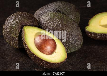 Moitiés d'avocat sur la table en pierre noire. Concept de graisses saines. Gros plan. Banque D'Images