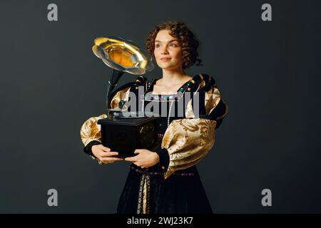 Portrait d'une jeune femme aristocratique vêtue d'une robe médiévale tenant un gramophone dans ses mains et écoutant de la musique classique Banque D'Images