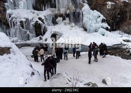 Baramulla, Inde. 12 février 2024. Touriste vu près d'une cascade partiellement gelée pendant une journée ensoleillée. Après un long hiver sec et chaud, la vallée a connu des chutes de neige et des pluies généralisées la semaine dernière. La vallée est actuellement dans la phase modérée de l'hiver, Chillai Khurd, après la fin de la période la plus dure de 40 jours le 30 janvier. Crédit : SOPA images Limited/Alamy Live News Banque D'Images