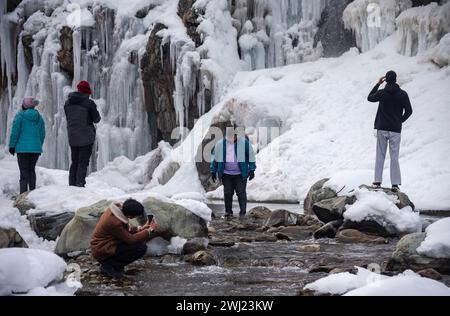 Baramulla, Inde. 12 février 2024. Les gens prennent des photos Infront de cascade partiellement gelée pendant une journée ensoleillée. Après un long hiver sec et chaud, la vallée a connu des chutes de neige et des pluies généralisées la semaine dernière. La vallée est actuellement dans la phase modérée de l'hiver, Chillai Khurd, après la fin de la période la plus dure de 40 jours le 30 janvier. Crédit : SOPA images Limited/Alamy Live News Banque D'Images